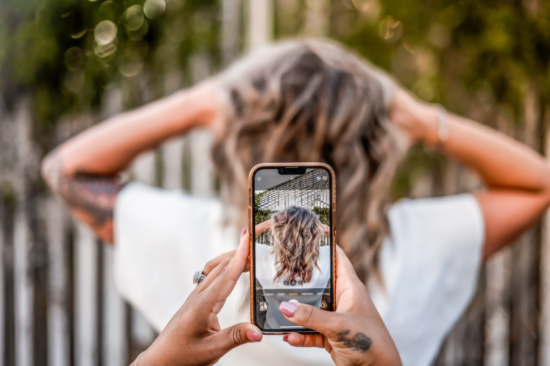 A guest snapping a phone photo of fresh wavy hair color, capturing inspiration to bring to a first appointment at A Shade of Vintage