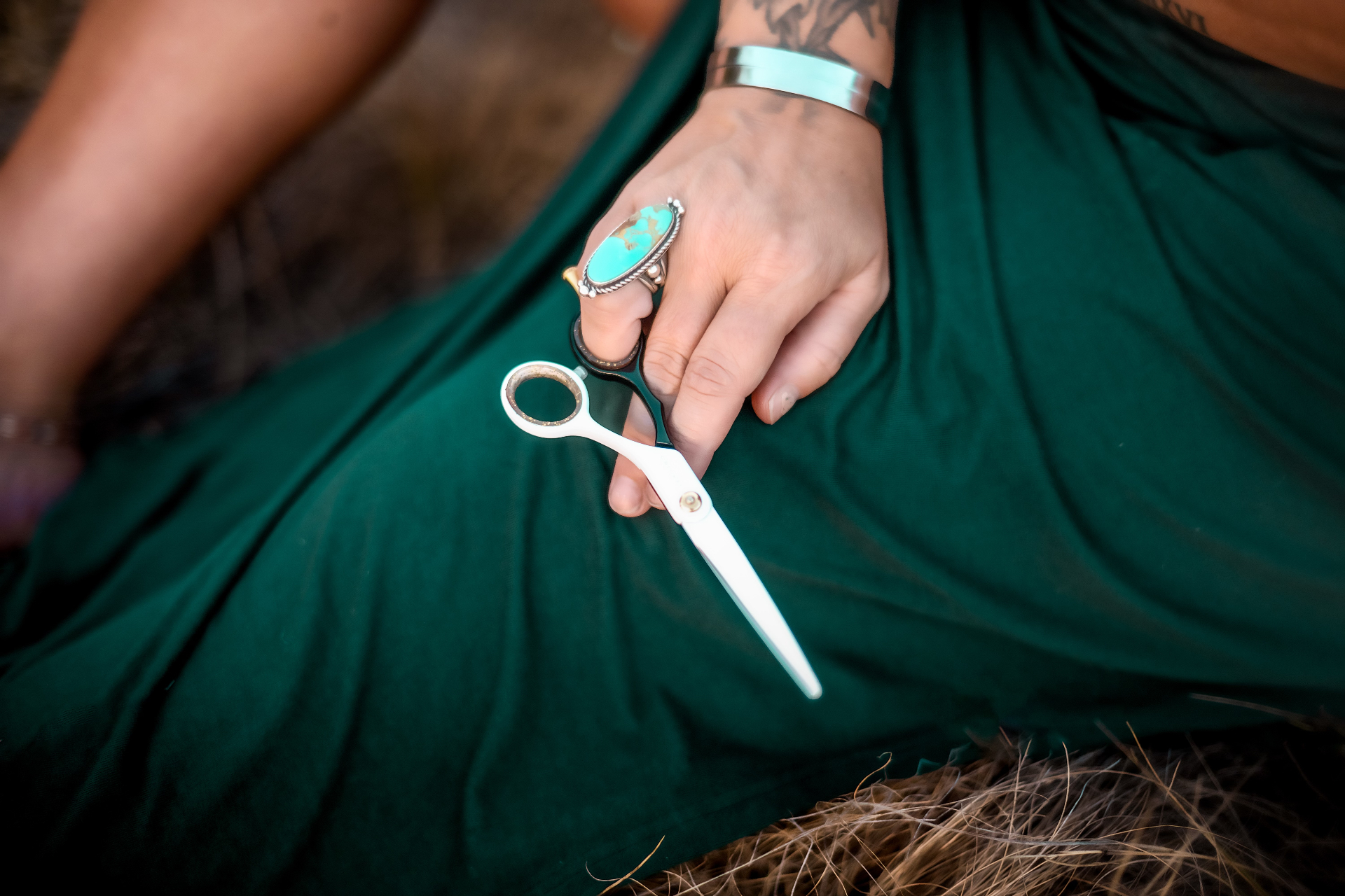 A stylist at A Shade of Vintage holding shears in a Wyoming field, symbolizing precision craftsmanship