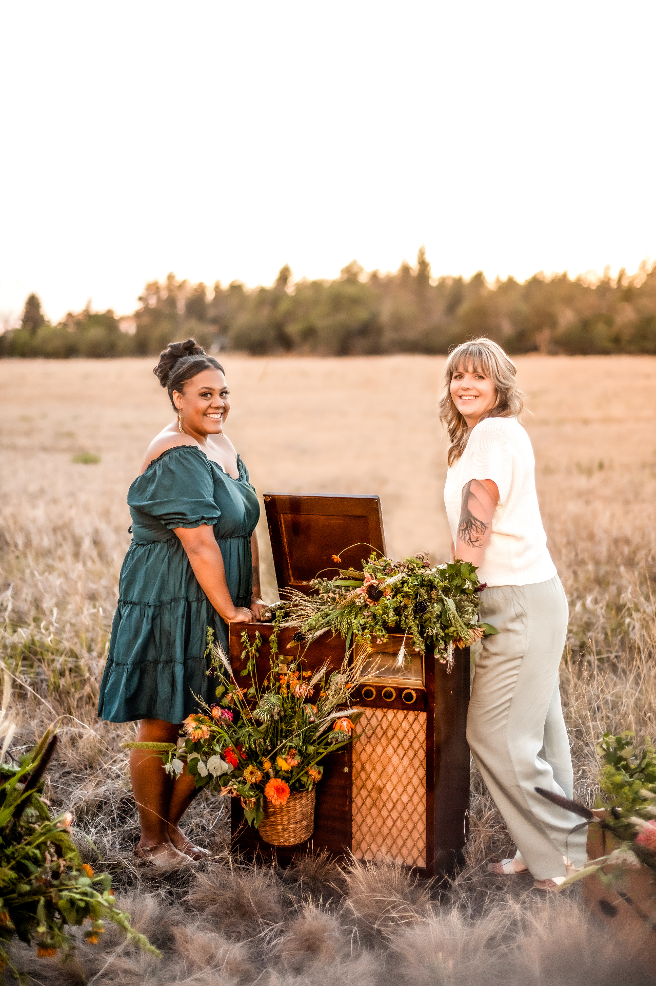 Two A Shade of Vintage stylists with a vintage record player and wildflowers in a Wyoming field at sunset